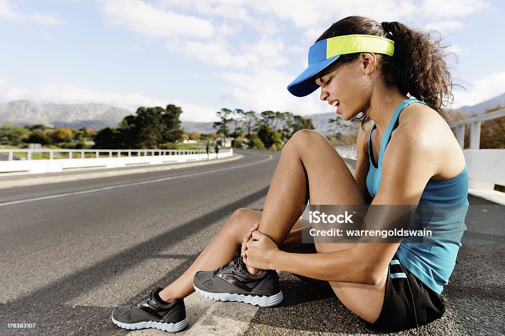 ankle injury athlete Runner with ankle injury has sprained and strained ankle, painful expression. typical road running problem associated with shoe choice Activity Stock Photo