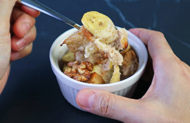 istock Hand Scooping Mouthwatering Banana Walnut Bread Pudding from a Ceramic Bowl 1783831820