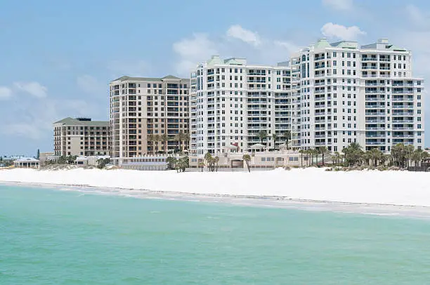 "High-rise hotels on Clearwater Beach, Florida from a Gulf of Mexico viewpoint. Beautiful clear blue water,  white sand beach and palm trees."