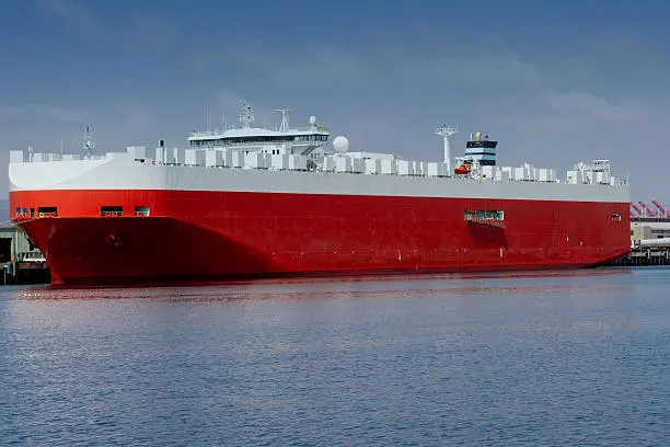 A large roll-on/roll-off (RORO or ro-ro) car carrier ship docked in a harbor