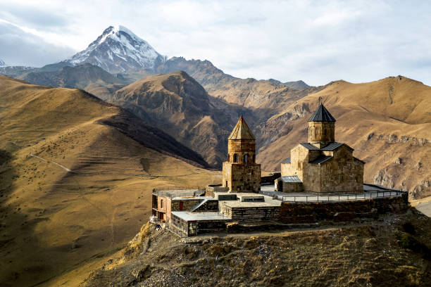A beautiful landscape of a historic church in the mountains with a snowy peak in the background. A beautiful landscape of a historic church in the mountains with a snowy peak in the background caucasus stock pictures, royalty-free photos & images