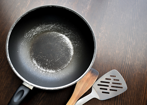 Old scratched non-stick saucepan on the table.