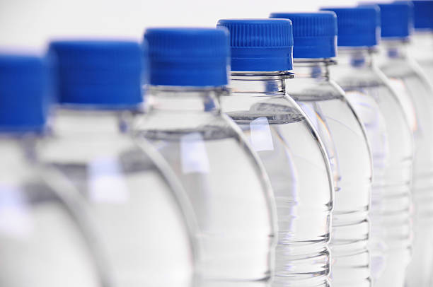 water bottle lids blurred select focus on middle bottle in a row of water bottles polyethylene terephthalate stock pictures, royalty-free photos & images