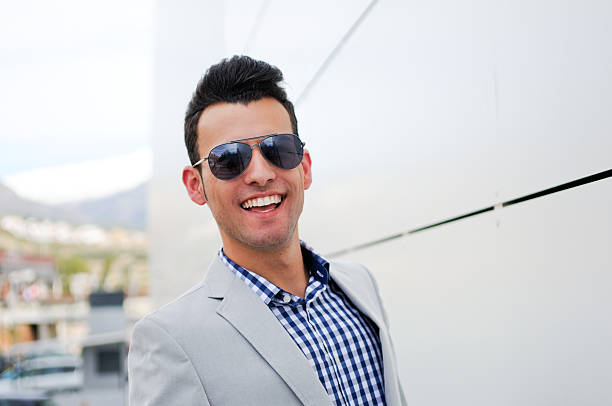 Attractive man with tinted sunglasses smiling "Portrait of a young handsome man, model of fashion, wearing tinted sunglasses" aviator glasses stock pictures, royalty-free photos & images
