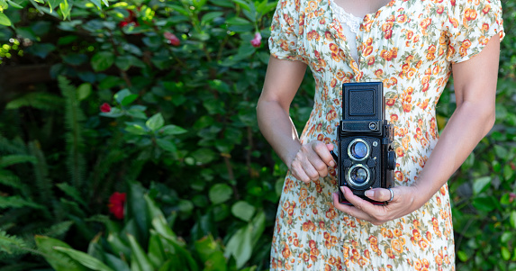 Woman taking pictures with a retro camera outdoor. Cropped portrait banner with copy space