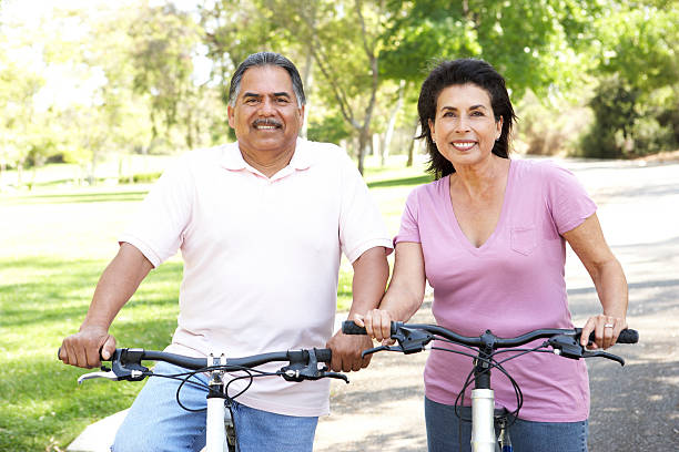 montar bicicletas de pareja senior en el parque - action mature adult bicycle senior couple fotografías e imágenes de stock