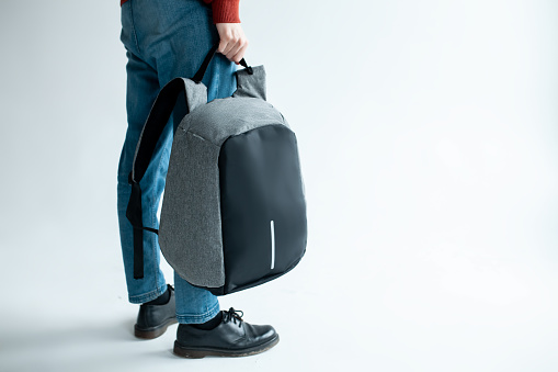 stylish hipster male holding modern backpack bag on white background