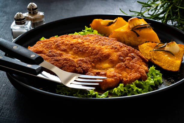 istock Breaded fried pork chop with baked pumpkin on wooden table 1783872170