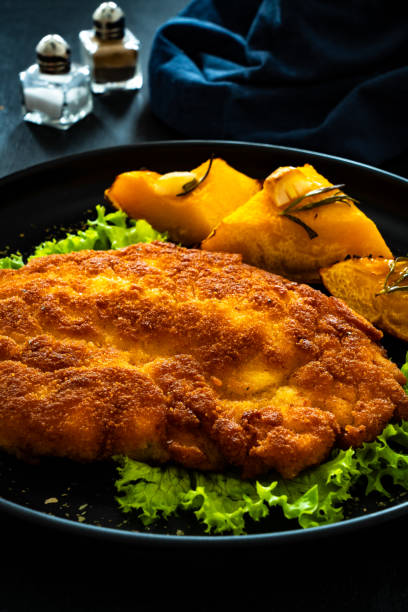 istock Breaded fried pork chop with baked pumpkin on wooden table 1783872734