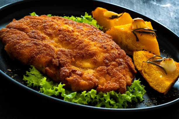 istock Breaded fried pork chop with baked pumpkin on wooden table 1783873974