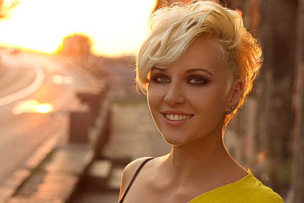 A portrait of an modern looking girl in a sunset with a smile on her face.