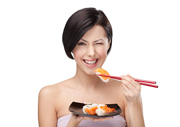 Woman winking and smiling while eating sushi with chopstick