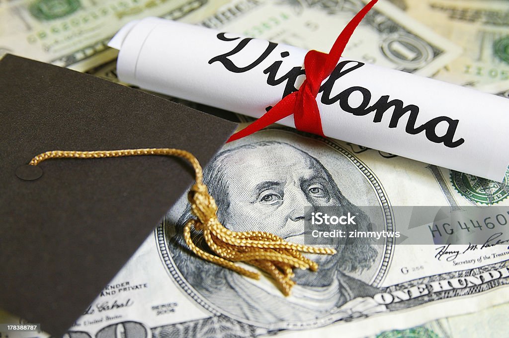 cap and diploma closeup of a mini graduation cap and diploma on money Cap - Hat Stock Photo