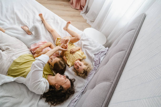 istock Mother playing with daughters in bed top view 1783889465