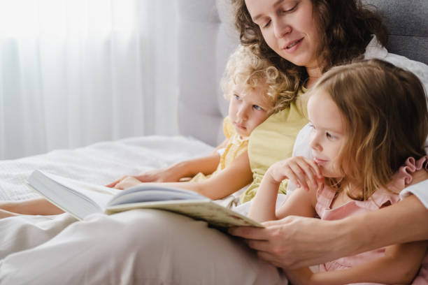 istock Mother reading a book her daughters at home 1783891145