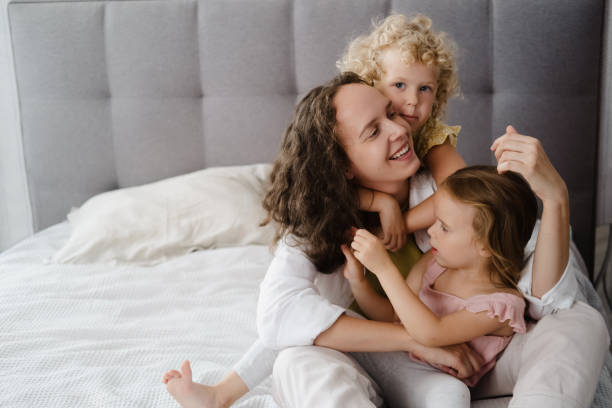 istock Mother hugging with two little daughters in bed 1783891759