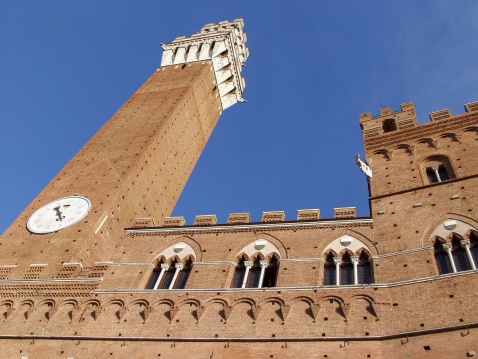A detail from below of Torre del Mangia in Siena - Italy. Famous clock tower in Piazza del Campo