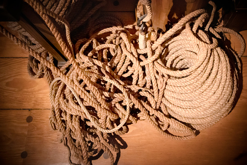 Different kinds of rope coiled on the wooden deck of an antique ship