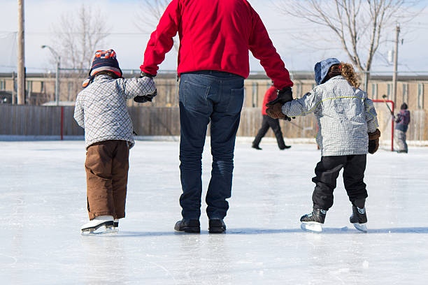Active family having winter fun at the ice skating rink stock photo