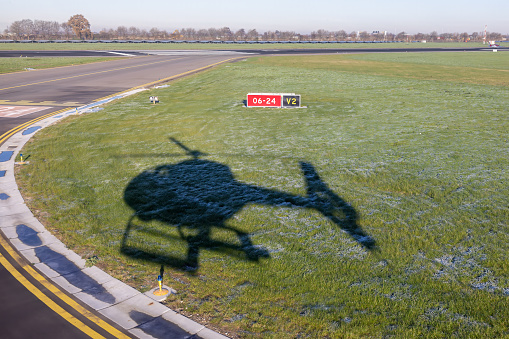 Shadow from take-off helicopter at grass near runway Dutch Airport Zestienhoven near Rotterdam