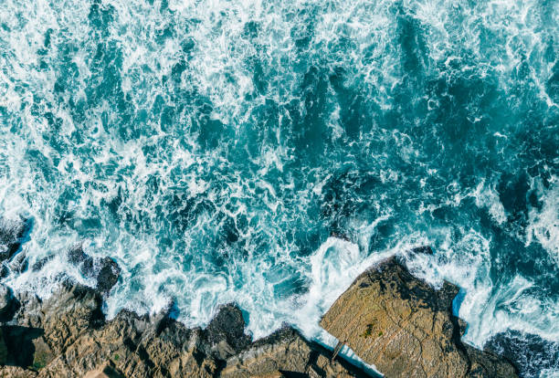 Aerial view of vortex created by waves of the rough ocean crashing on rocks