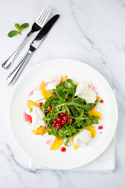 istock arugula salad with peach slices and red berries on a white plate top view 1783911293