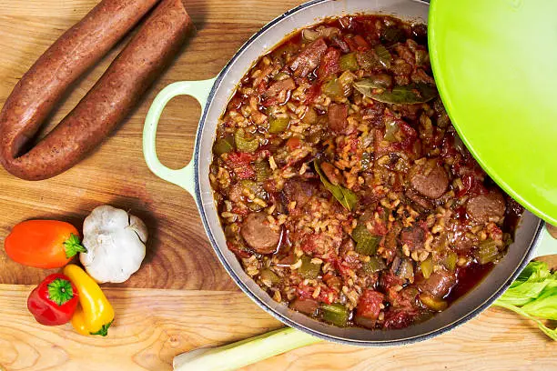 "Pot of jambalaya on cutting board with andouille sausage, garlic, bell peppers and celery."
