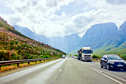 Cape Town, South Africa - November 6, 2023: Vehicles traverse the N1 national road near Cape Town, South Africa, with the majestic mountain range of Du Toit's Kloof forming a breathtaking backdrop as they approach the north end of the long tunnel that runs through the mountains beneath the old route called Du Toit's Kloof Pass.