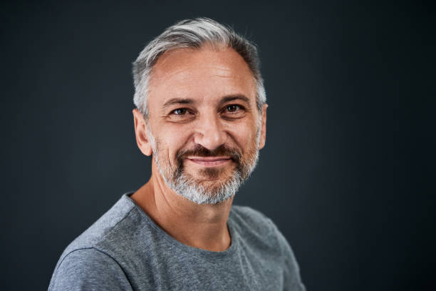 istock A smiling senior man, posing on the grey background, dressed in a grey sweater. 1783930954