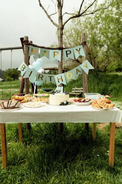 Photo of catering for the first birthday. inscription, happy birthday. holiday table with food and snacks, holiday table, concept in rustic style, picnic in nature in honor of the birthday