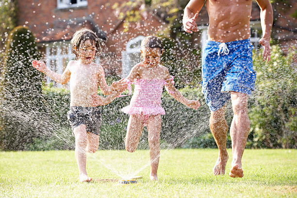 istock Father And Two Children Running Through Garden Sprinkler 178393247
