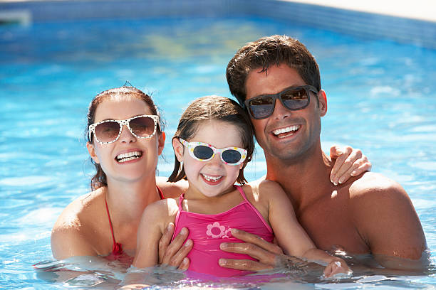 Family Having Fun In Swimming Pool Family Having Fun In Swimming Pool Wearing Sunglasses Smiling At Camera half dressed girls pictures stock pictures, royalty-free photos & images