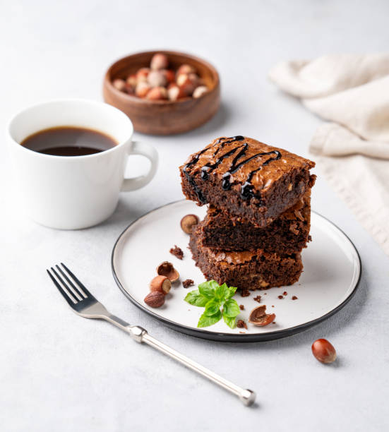 istock A stack of chocolate brownies with mint, hazelnuts and salted caramel on a plate on a light background with a cup of coffee and nuts. 1783933683