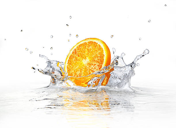 Orange slice falling and splashing into clear water. stock photo