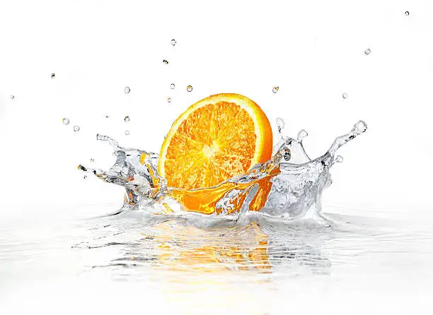 Orange slice falling and splashing into clear water. On white background.