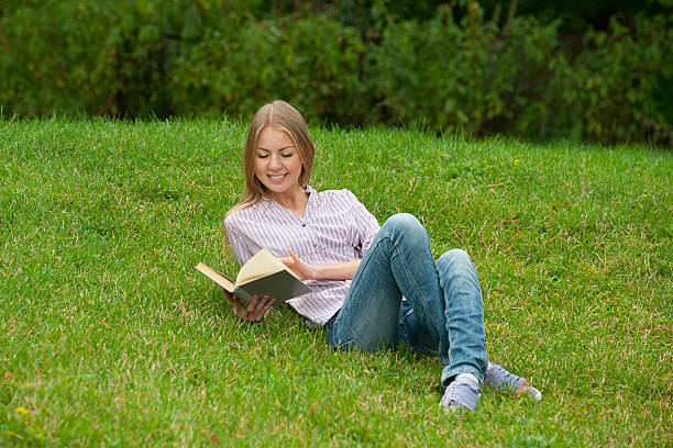 istock Young woman reading book outdoors 178393551