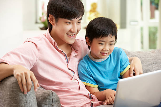 istock Chinese Father And Son Using Laptop Whilst Relaxing On Sofa 178393842