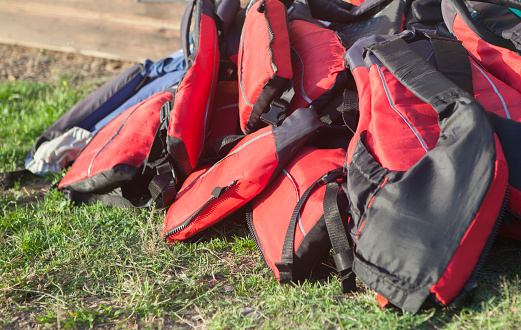 Life jackets piled up on the grass. Active tourism at freshwaters coasts concept