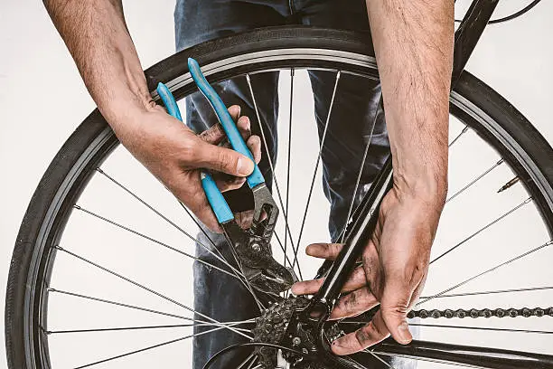 Isolated closeup of a man's grimy hands repairing a bicycle tire, on a white background