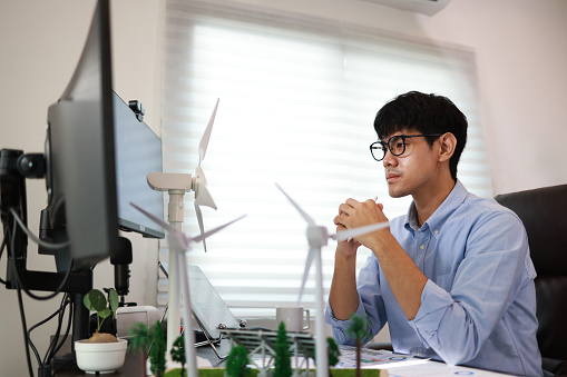 A young male design engineer working with 3D Wind Turbine Model technology and environment.
