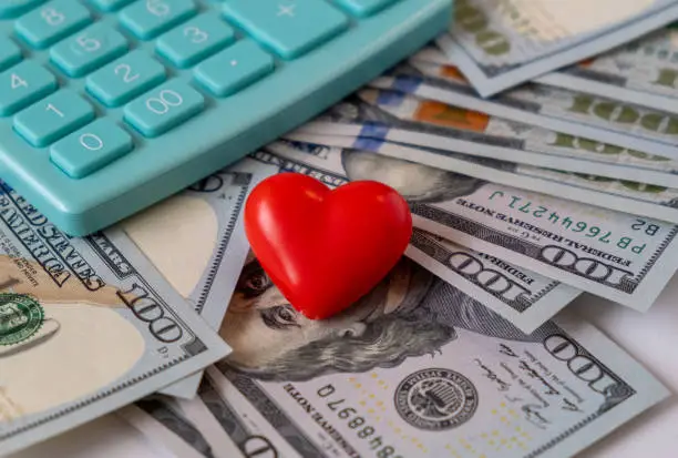 Photo of Red heart on banknotes on table with calculator, Valentine's Day gift planning, Budget for Valentine's Day