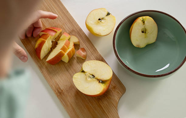 istock Young woman's hands cutting an apple on wooden cut board 1783965038