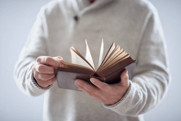 istock Man holding reading open holy bible or book with gray background 1783966321
