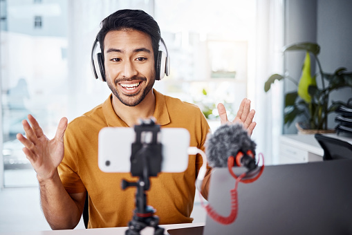 Podcast, happy and live streaming with a man content creator recording a broadcast in his home office. Internet, freelance and subscription with a male vlogger or creator working in his studio