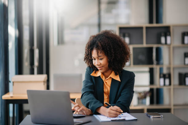 istock Confident beautiful Asian businesswoman typing laptop computer and digital tablet while holding coffee at office 1783968045