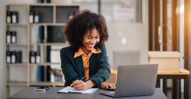 istock Confident beautiful Asian businesswoman typing laptop computer and digital tablet while holding coffee at office 1783972190