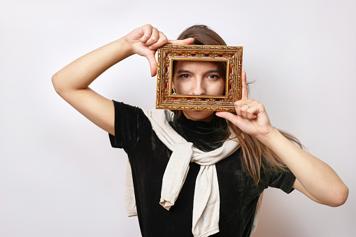 A beautiful girl poses for the camera, looking into a photo frame.