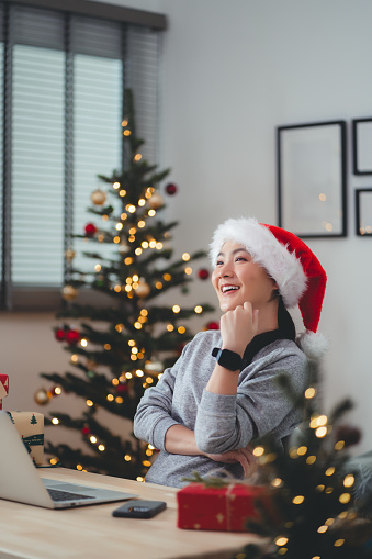 Asian woman having positive thinking happy with relax time sitting at home office decorated with a Christmas tree.