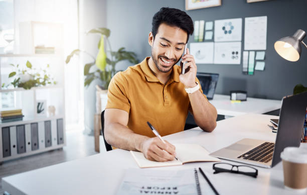 istock Phone call, happy and Asian man writing notes for reminder, schedule and planning at office desk. Communication, business and male worker on smartphone talking, in discussion and consulting for help 1783986771