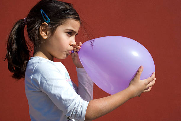 Girl blowing up balloon Mixed race girl blowing up balloon moroccan girl stock pictures, royalty-free photos & images